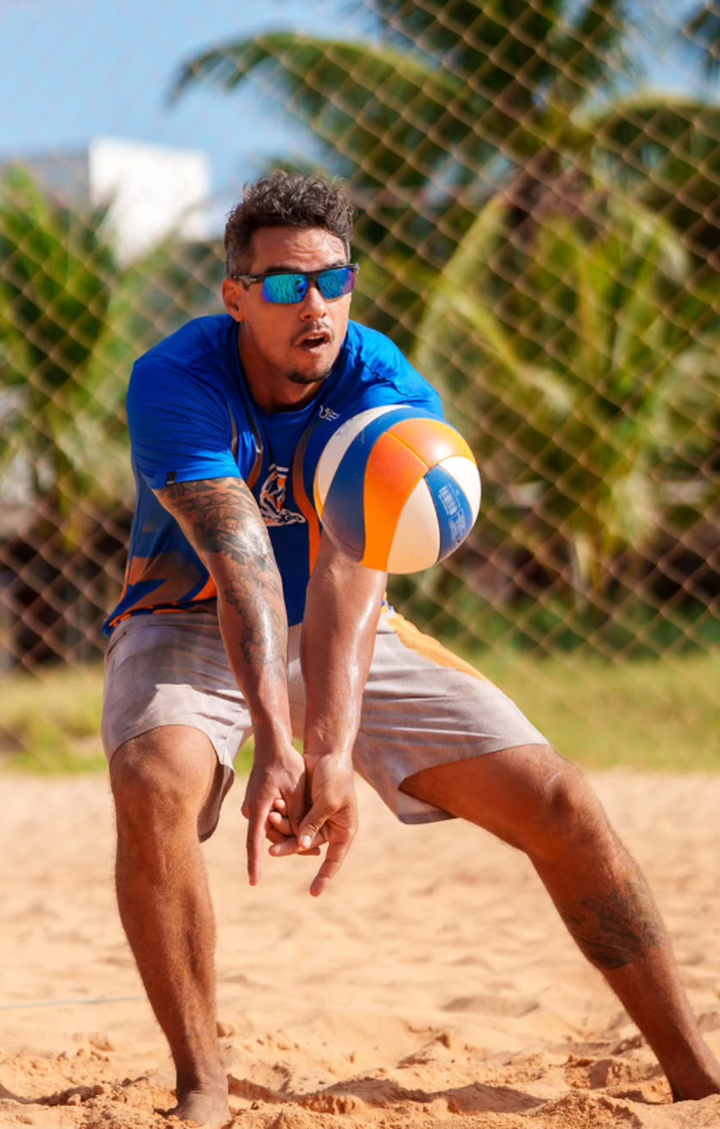 Bruno fazendo manchete na areia com camisa azul